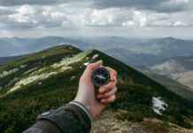 Wanderlust & Time-Honored Tales: A Fusion of Tradition and Travel person holding silver compass, Mountains is always right destination